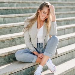 femme blonde posée sur des marches la main dans les cheveux