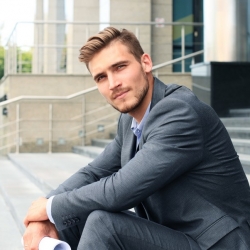 home en costume gris qui pose sur des escaliers